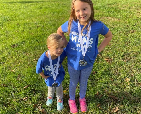 Two children posing, wearing medals in field.