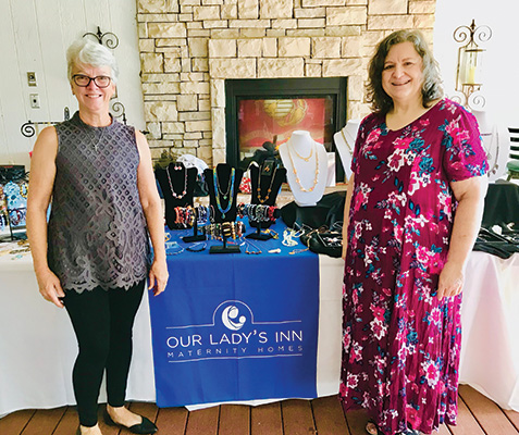 Women in front of OLI Pay It Forward jewelry table